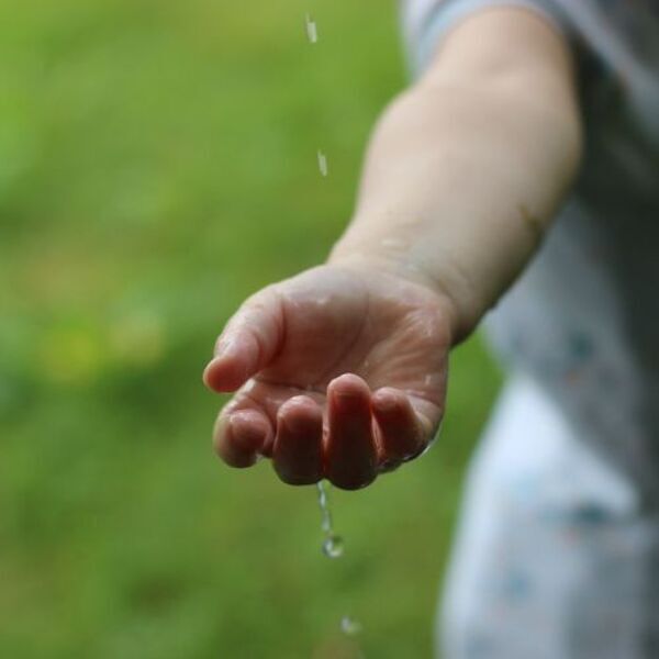 rain / Thaliesin_pixabay.com Kinderhand mit fallenden Wassertropfen